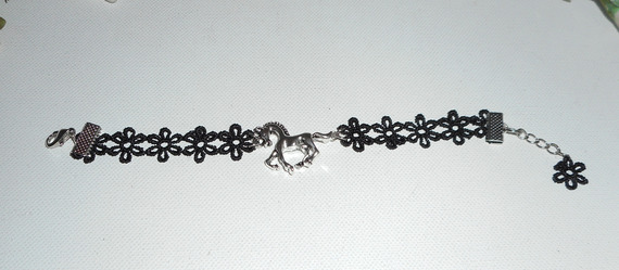 Originelles Armband mit silbernem Metallpferd auf schwarzer Spitze